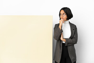 Young business mixed race woman with with a big banner over isolated background having doubts and with confuse face expression