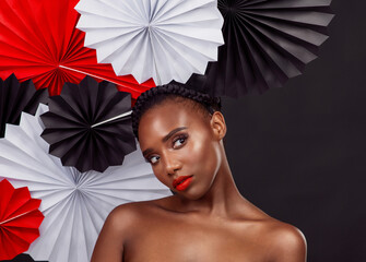 Woman, thinking and beauty with origami fans in studio isolated on a dark background. Face, makeup...
