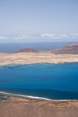 Views of the island of La Graciosa from the viewpoint of El Rio. Turquoise ocean. Blue sky with big white clouds. Caleta de Sebo. Town. volcanoes. Lanzarote, Canary Islands, Spain