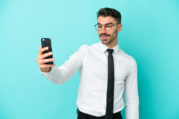 Business caucasian man isolated on blue background making a selfie