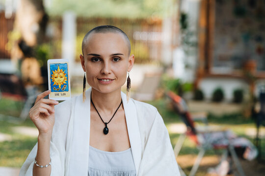A bald woman tarot reader show a tarot card The sun
