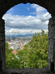 Ljubljana cityscape and Julian Alps mountains view from stone wall window in sunny spring Slovenia