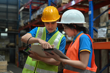 Two workers using digital tablets to check the stock inventory in warehouses, management system, and logistic concepts