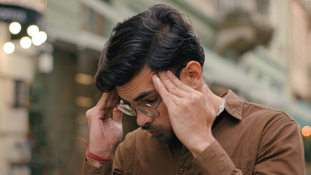 Annoyed angry mad stressed Indian Arabian ethnic male student man guy businessman client customer furious business fail loss dissatisfaction frustration headache touch holding head outside city street - Powered by Adobe