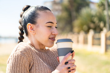 Young moroccan girl  at outdoors holding a take away coffee with happy expression