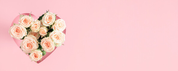 Festive light background with beautiful small roses. White roses and heart frame on pastel pink...