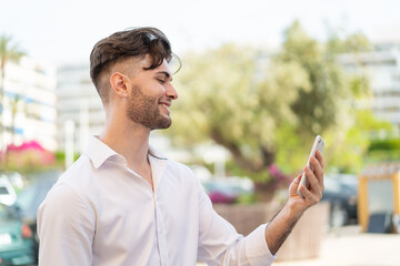Young handsome man using mobile phone at outdoors with happy expression