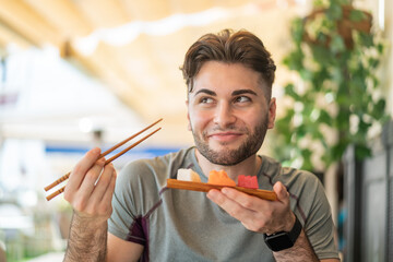 Young handsome man holding sashimi at outdoors