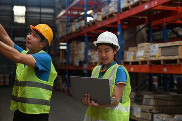 Two Warehouse employees check and count the stock inventory on a laptop, a Smart Warehouse...