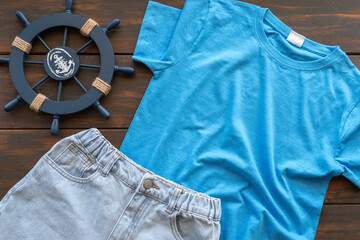 Blue shirt and jeans short for kids over dark wooden background. Summer outfit for children..