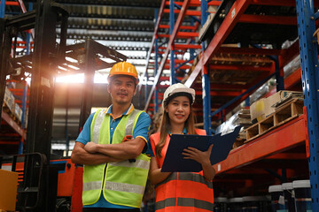 Portrait of a confident forklift truck with a male driver with arms crossed and a smiling female...