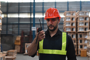 Portrait of Caucasian factory worker or engineer man using walkie talkie and talking about work in...