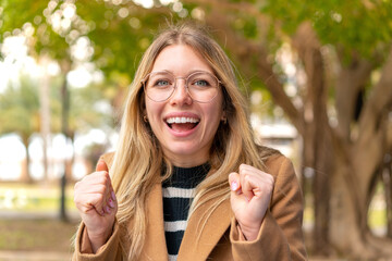 Young pretty blonde woman at outdoors celebrating a victory in winner position