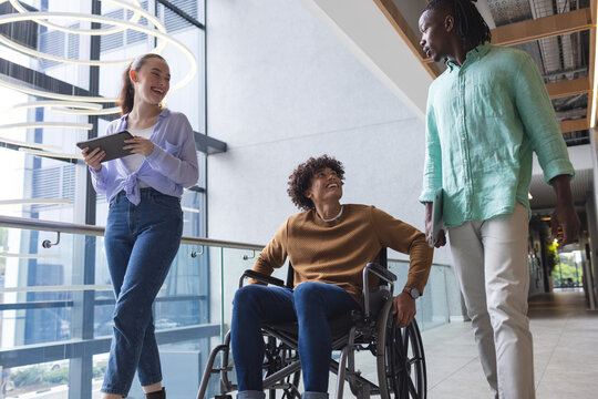Diverse colleagues walking and talking in bright hallway in a modern business office