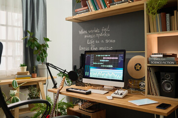 Workplace of creative musician composing music and writing lyrics with help of audio software, microphone and musical instruments