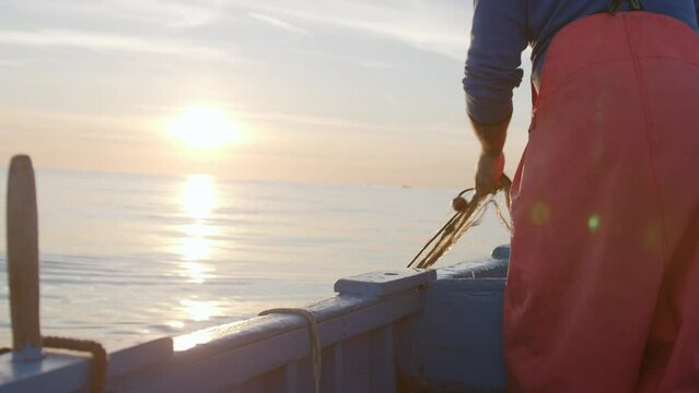 Fisherman on Boat at Dawn with Sunrise Over the Ocean