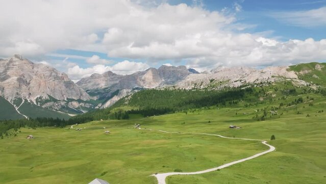 Aerial cinematic footage of the lush green meadows of Pralongia in the Italian Dolomites. Drone is flying forward revealing old cottages and winding unpaved roads and paths. LuPa Creative.
