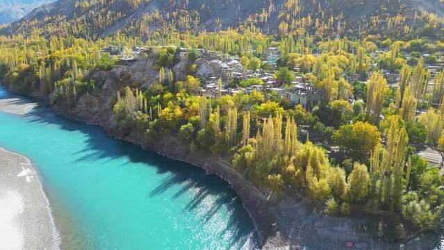 Drone shot over Skardu in pakistan turquoise river and green trees with mountains in the background