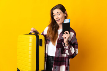 Young Ireland woman isolated on yellow background in vacation with suitcase and passport