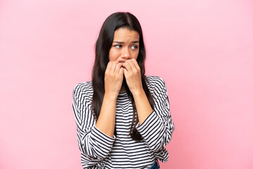 Young Colombian woman isolated on pink background nervous and scared putting hands to mouth