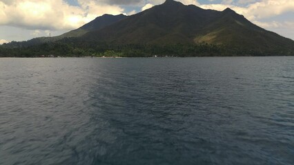 Low level flight over the ocean with tilt up reveal flying towards Sabang boat terminal.