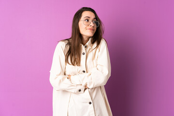 Young woman over isolated purple background making doubts gesture while lifting the shoulders