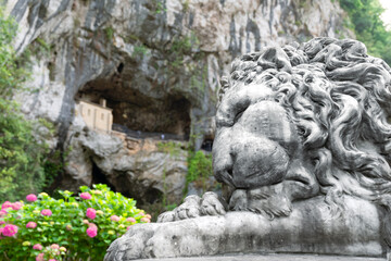 A lion statue is resting on a rock in front of a cave Enol lakes in covadonga asturias