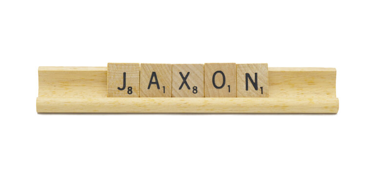 Miami, FL 4-18-24 popular baby boy first name of JAXON made with square wooden tile English alphabet letters with natural color and grain on a wood rack holder isolated on white background