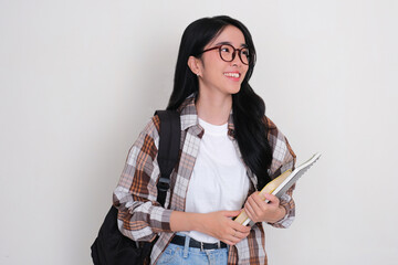 Female college student bring books and carrying backpack smiling while looking beside her