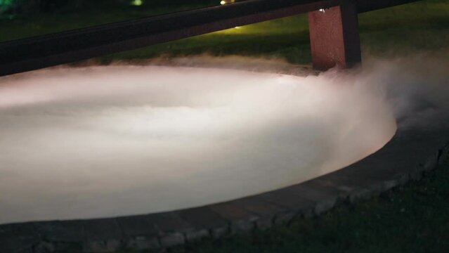 Mystical dry ice fog flowing over pool edge at night