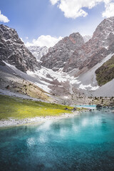 Mountain panorama, landscape with rocky peaks and blue turquoise lake Ziyorat in the Fan Mountains in Tajikistan, on a sunny summer day