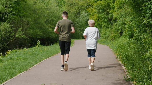 An elderly woman with a young man jogging in the park. Active seniors concept