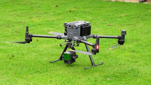 Large industrial drone with lidar system camera payload on green grass