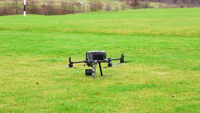 Heavy industrial drone landing on green grass field with advanced camera payload