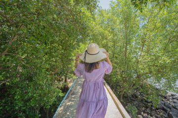 Obraz premium Portrait of Asian woman travel at lush green trees in tropical forest in national park in summer season. Natural landscape.