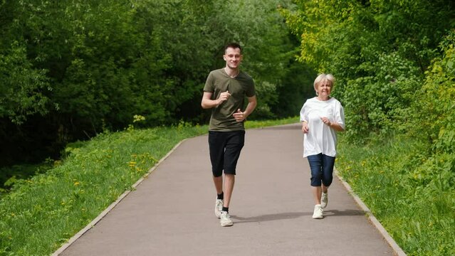 An elderly woman with a young man jogging in the park. Active seniors concept