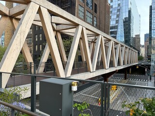 Wooden bridge spanning a city road with modern buildings in the background