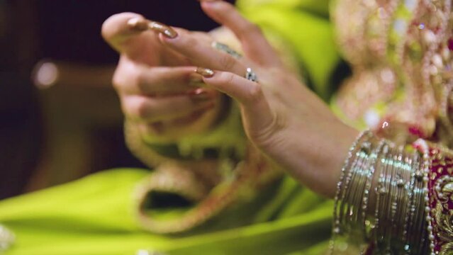 An up-close view of the ring-studded hands of an Asian bride in costume.