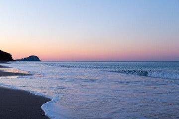 Sunrise at the Yanışlı beach on the background of  orange sky and waves come ashore of the Mediterranean Sea at the long exposure