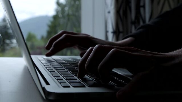 Close-up shot of a man typing on his MacBook.