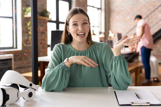 Caucasian female young professional sitting, explaining with hands in a modern business office on vi