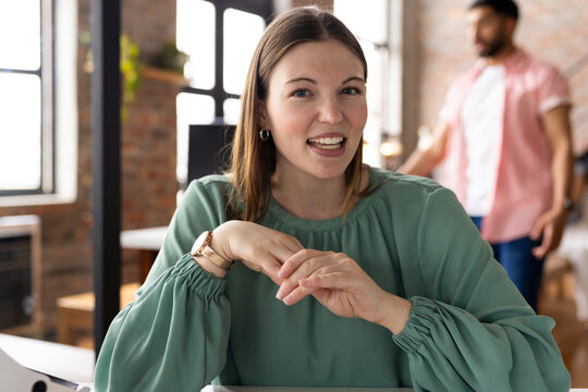 Caucasian female young professional sitting, smiling, wearing green top in a modern business office 