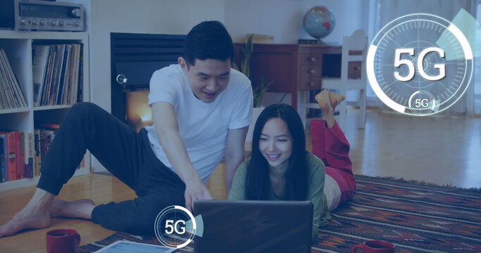 Image of multiple digital 5G icons over couple using laptop at home