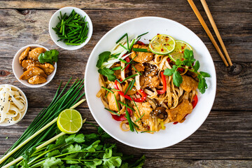 Asian food - chicken nuggets, noodles and stir fried vegetables on wooden table

