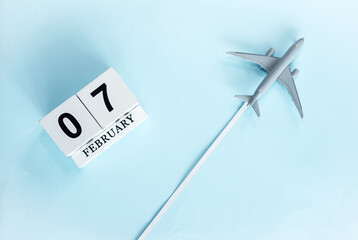February calendar with number  7. Top view of calendar with flying passenger plane. Scheduler....