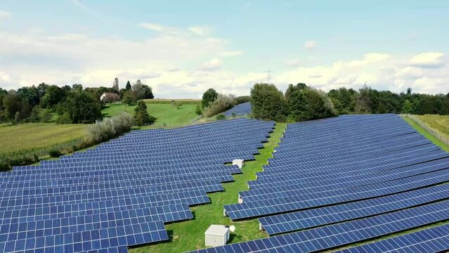 Retreating aerial view over photovoltaic system, farmland surrounding.