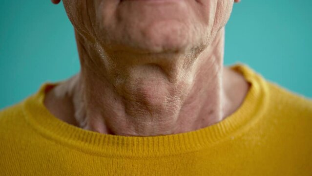Close-up of an elderly man swallowing an Adam's apple, larynx and throat in the process of swallowing