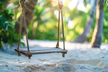 Wooden swing hanging from a palm tree above the soft white sand of the tropical beach.