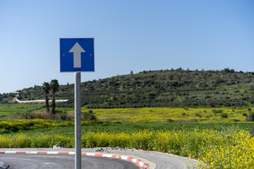 Solitary blue road sign with an upward arrow points the way forward amidst a backdrop of a curving...