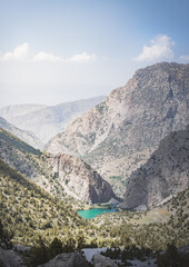 Panoramic landscape in the mountains with rocks and scree, with grass glades, snow and glaciers on a sunny summer day in the Fann Mountains in Tajikistan with mountain ranges